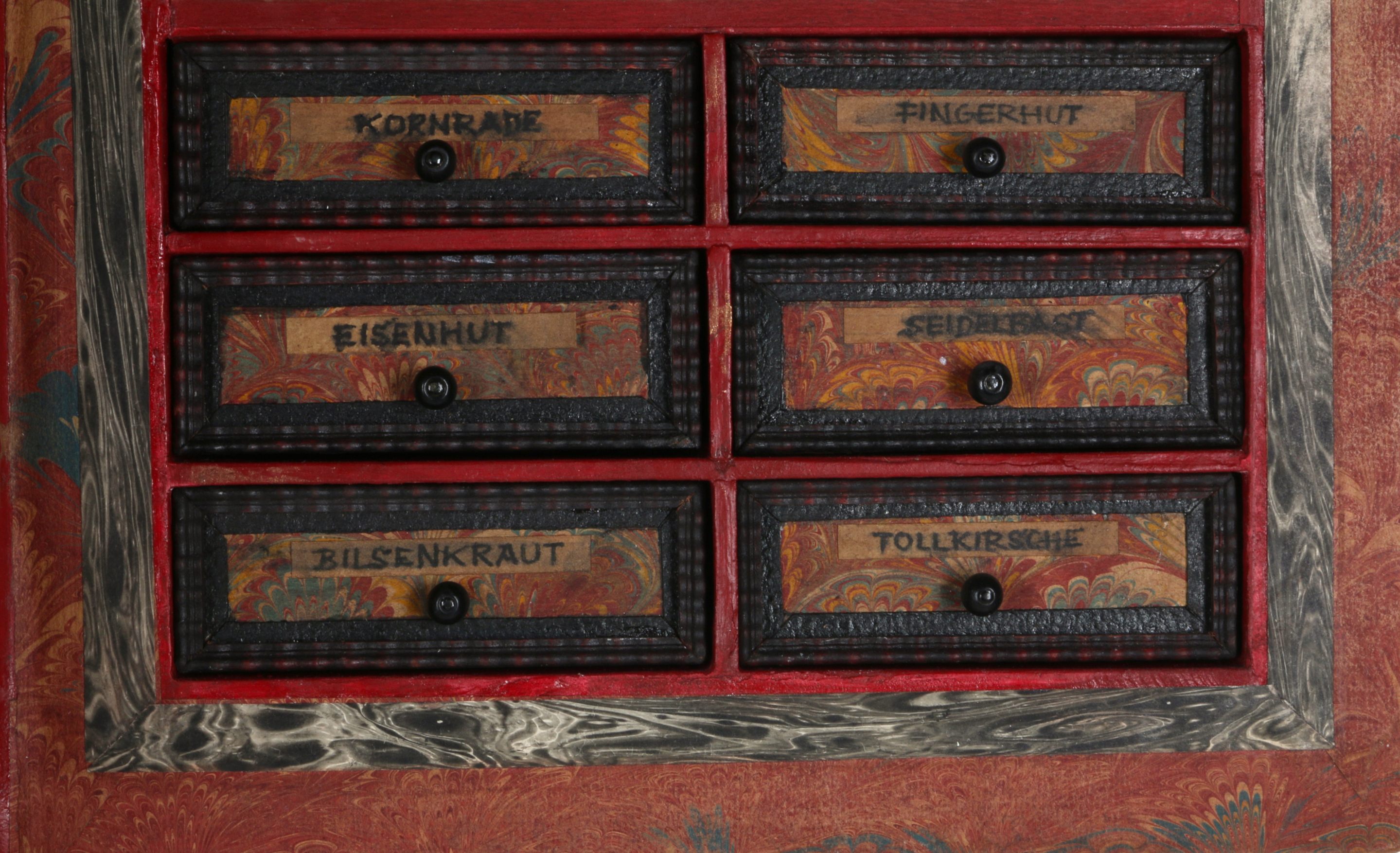 The little drawers include the German words for foxglove, belladonna, and other potential poisons.