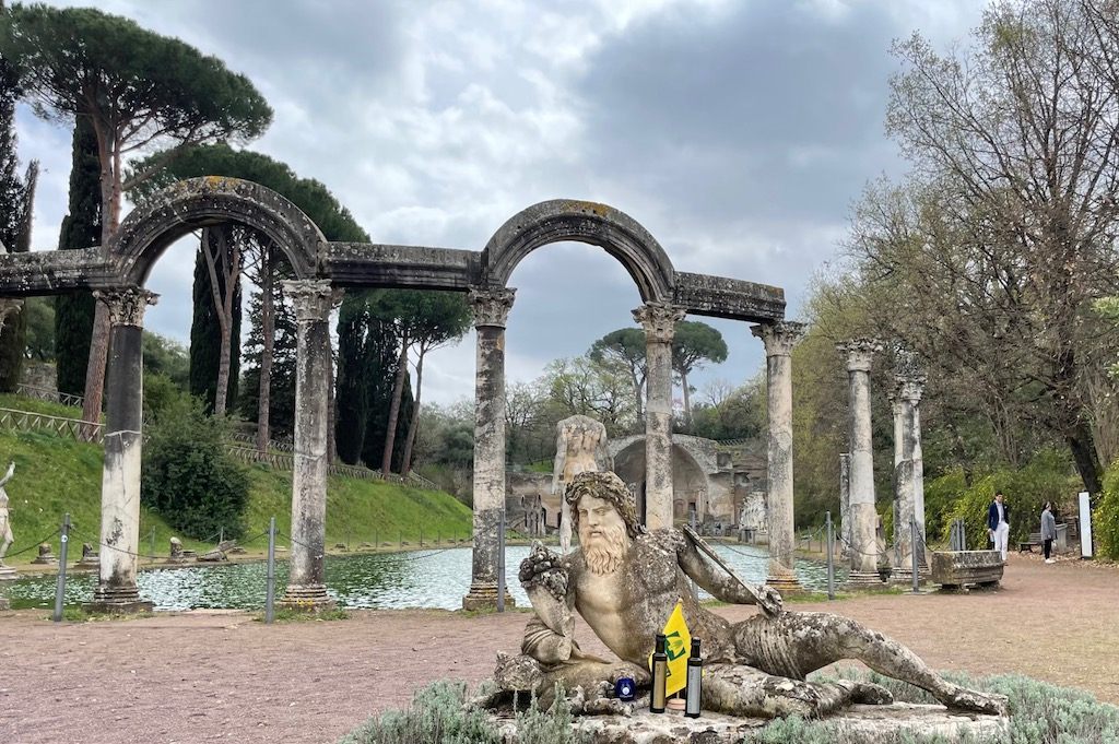Two bottles of Olea Hadriani by a statue representing the Tiber river in the Villa’s Canopus.