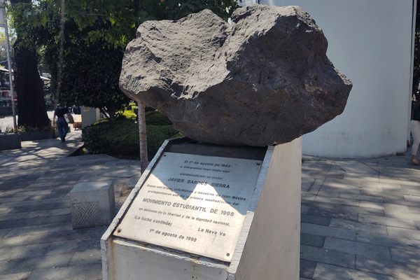 A volcanic rock sits on a pedestal in a park
