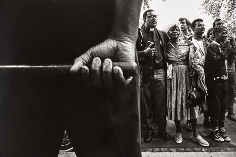 Protesters, seen from behind a police officer.