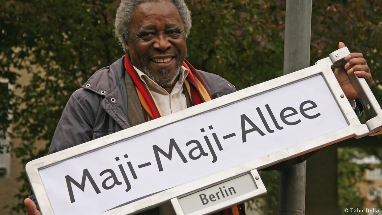 Mnyaka Sururu Mboro, of nonprofit Berlin Postkolonial, holds a sign for a street renamed to commemorate a rebellion in German East Africa. 