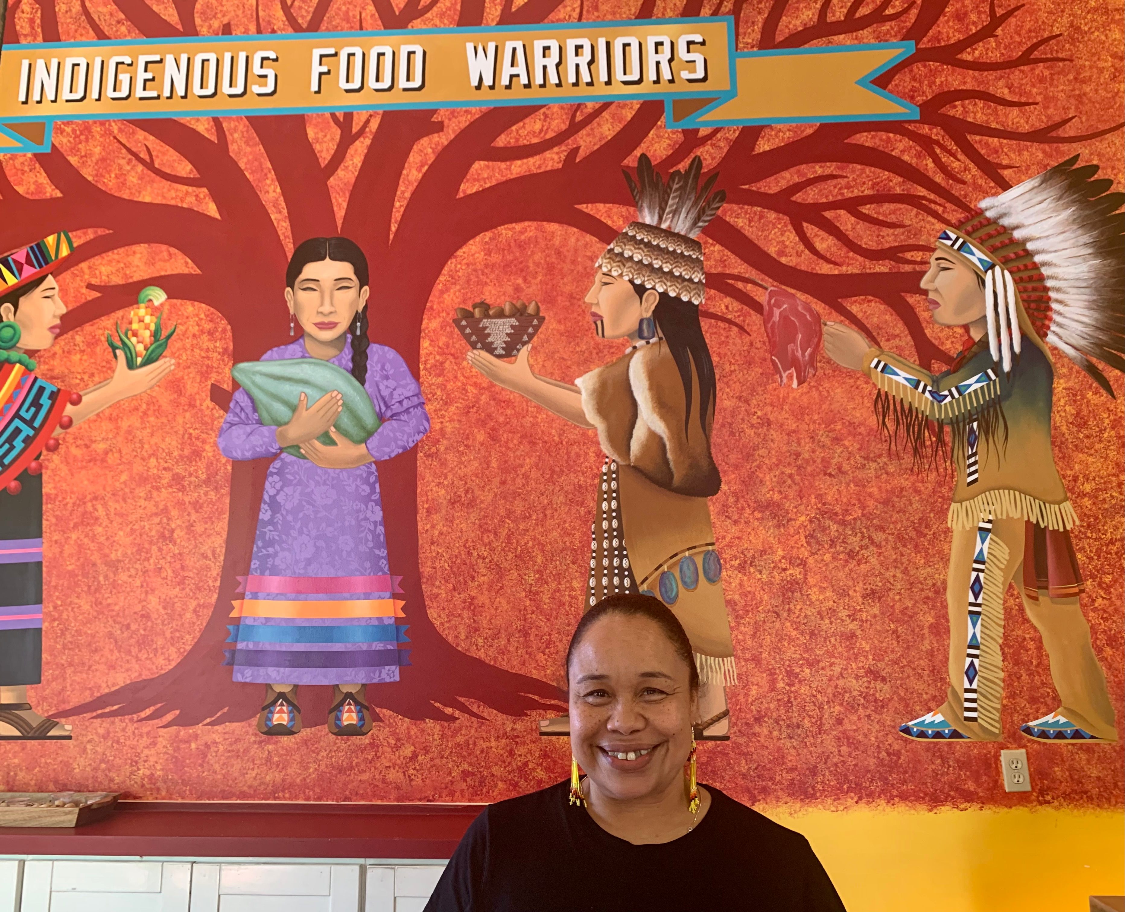 Crystal Wahpepah, in front of the mural at her restaurant.