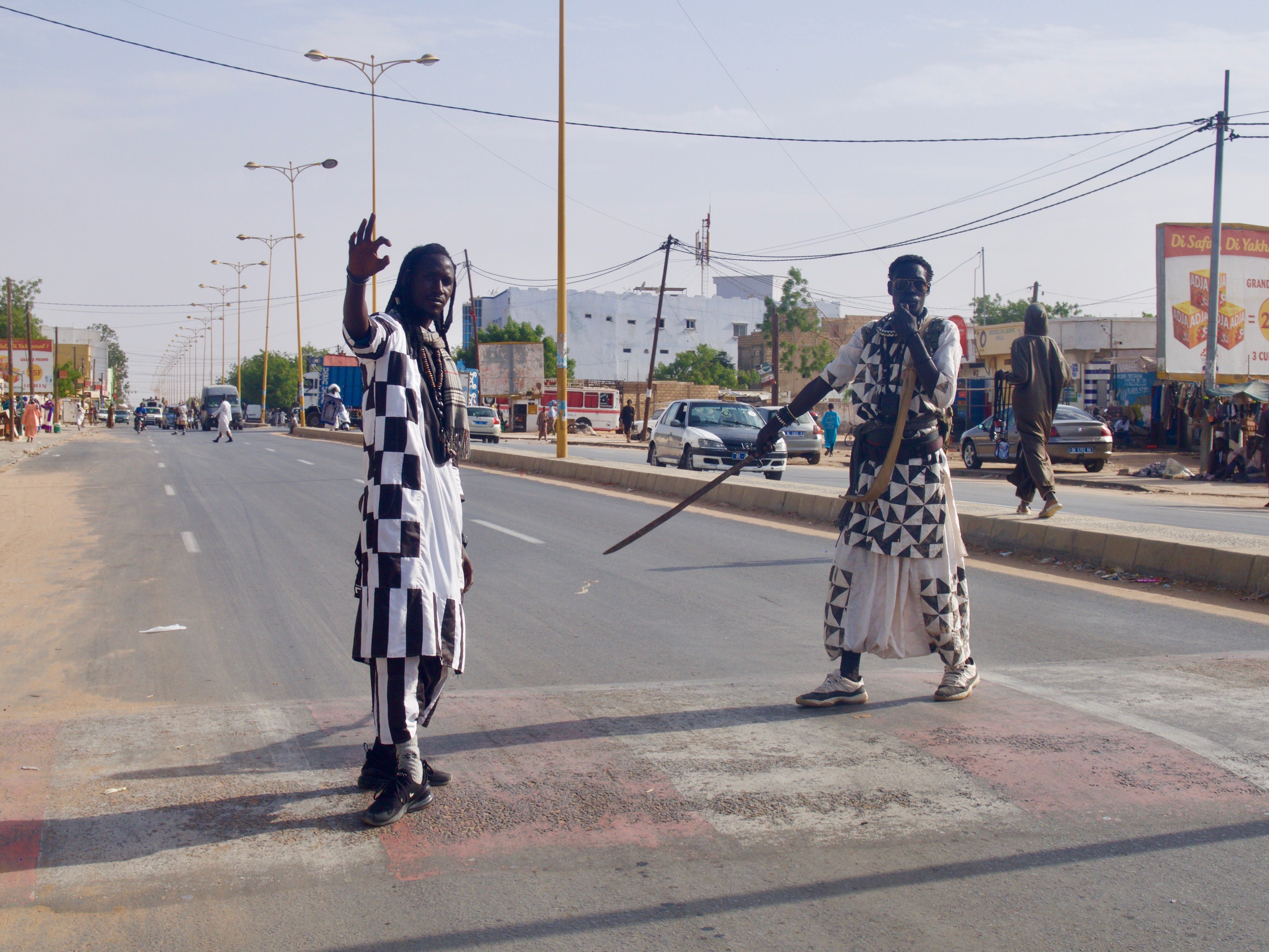 Two of the Baye Fall prepare to stop traffic so the group can march to the Mosque.