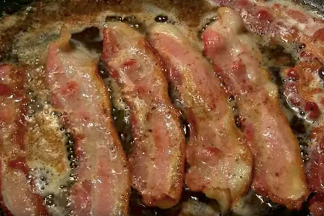 Bacon on bacon sizzles on the stovetop.