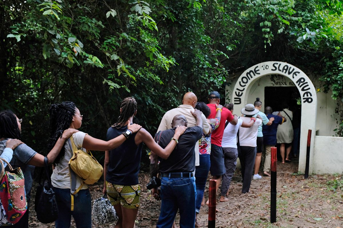 Members of a tour group enact how slaves were transported at Assin Manso.