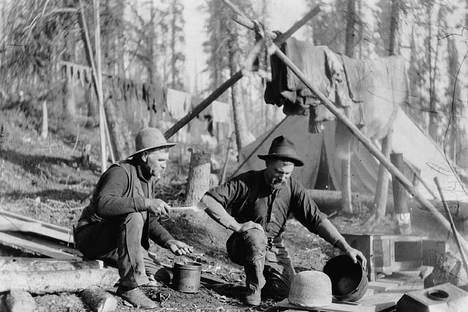 An Alaskan miner bakes a loaf, likely of sourdough, in 1898.
