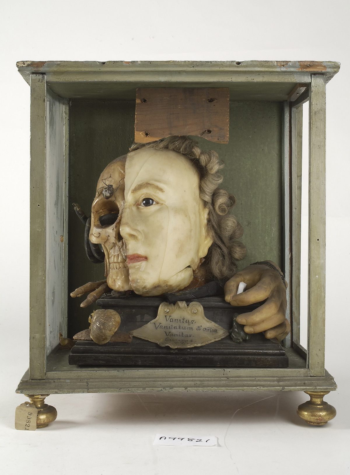 An 18th-century wax tableau, with one half resembling Queen Elizabeth I, the other a skull crawling with insects. The text below is drawn from Ecclesiastes 1:2, "Vanity of vanities, is all vanity." 