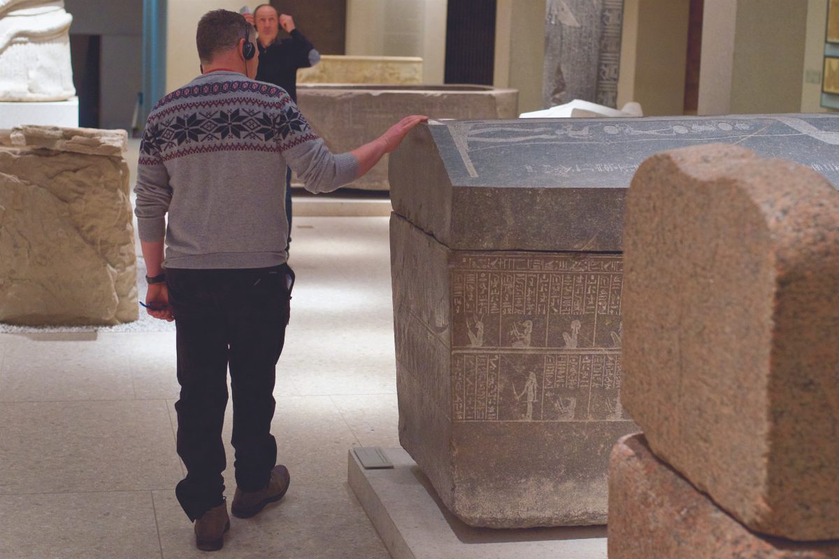 A man runs his hand along a carved sarcophagus at the Neues Museum in Berlin.
