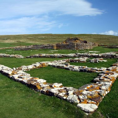 The remains of houses with the church and, on the left, the replica Pictish stone.
