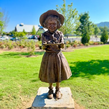 The bronze statue of Little Debbie depicts the character holding a tray of Swiss Rolls.
