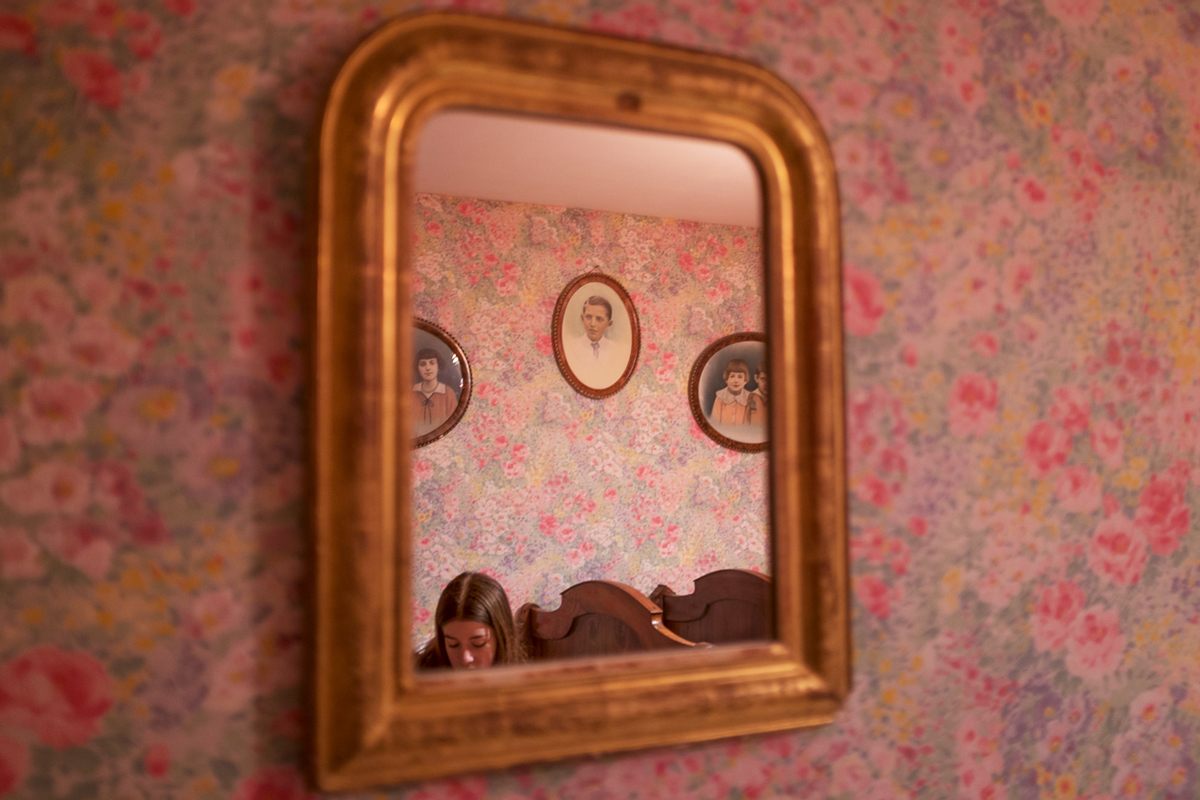 Madeleine Bibal, 12, is seen in the mirror flanked by portraits of family members in what was once her grandfather's bedroom.