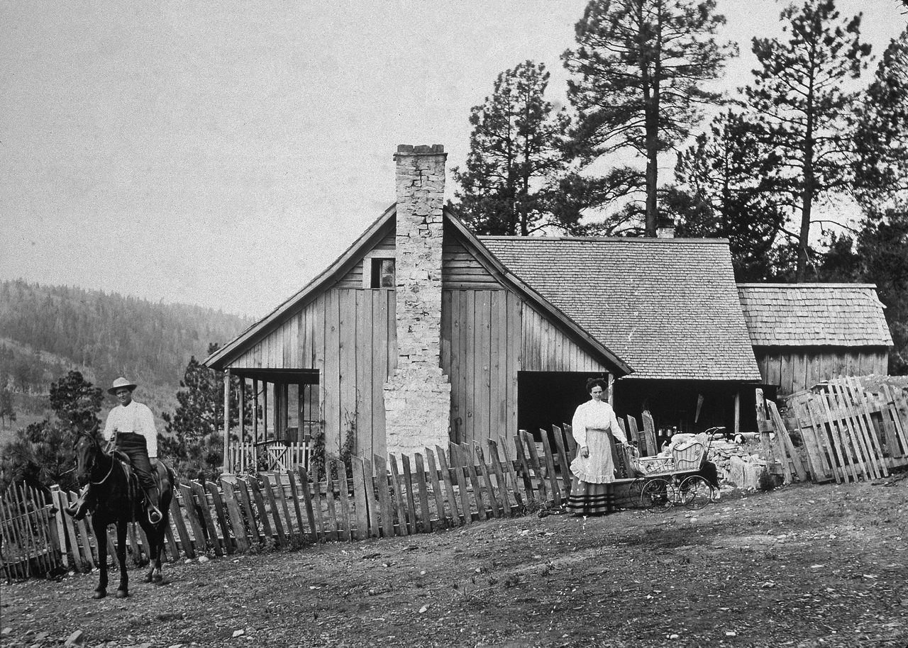 A family poses outside their homestead, somewhere out west, in the late 19th century. 