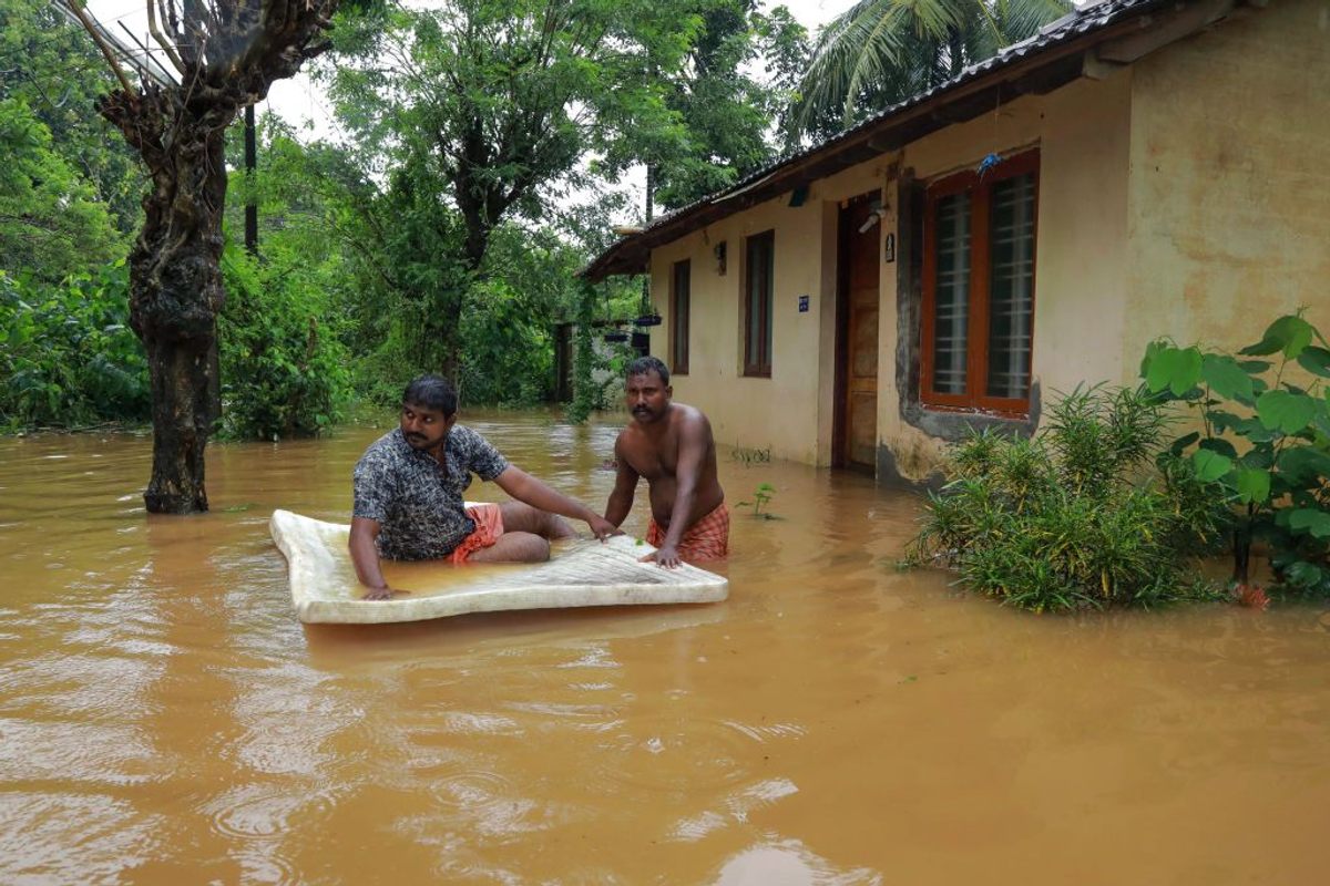 Men pass through floodwaters in the Ernakulam district of Kerala on August 9, 2019.