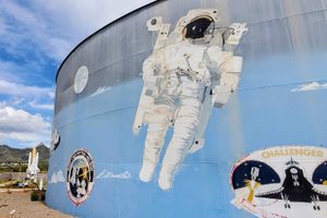 An astronaut orbits a water tank in the rural New Mexico mountains.