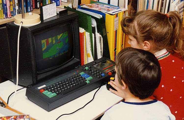 1988: Children playing Amstrad CPC464 computer. Data and programs were input with the built-in tape reader on the right of the keyboard. The game on screen is Paperboy.