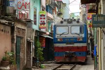 Diesel train coming down the train tracks through a narrow street in Hanoi.