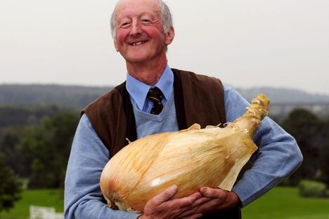 Peter Glazebrook cradles one of his creations, an 18-pound onion that won the world record in 2012. 