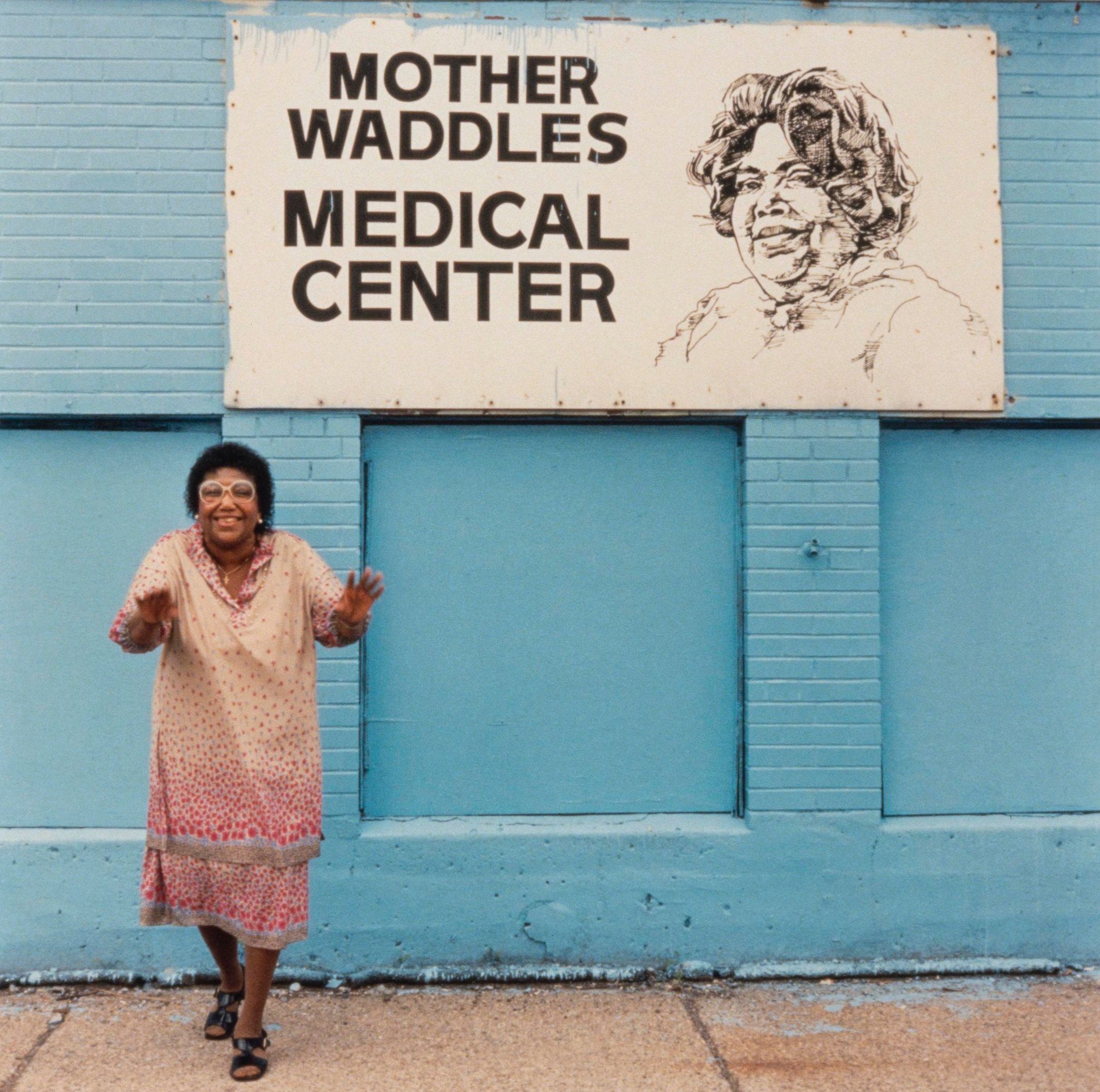 Waddles in front of the health center she founded.