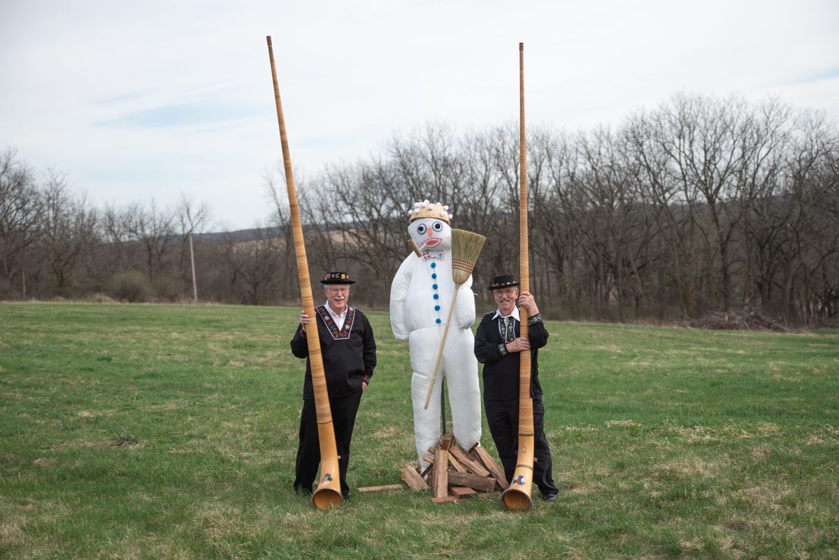 Two men pose with their alphorns next to New Glarus's Bӧӧgg. Alphorns may have originated from a Roman-Etruscan curved war horn known as a <em>lituus</em>.