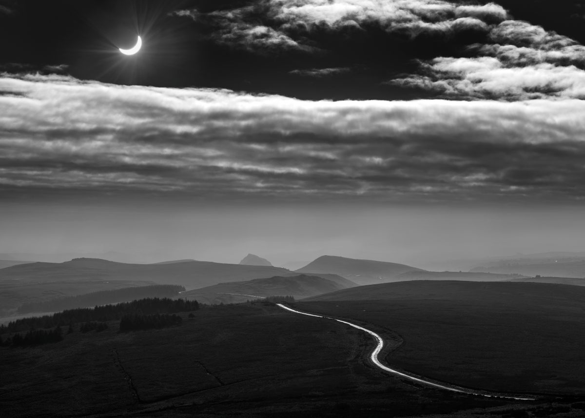 A winding road in England's Peak District National Park leads the way to an eclipse in progress—Which road will you take to witness the next big celestial event?