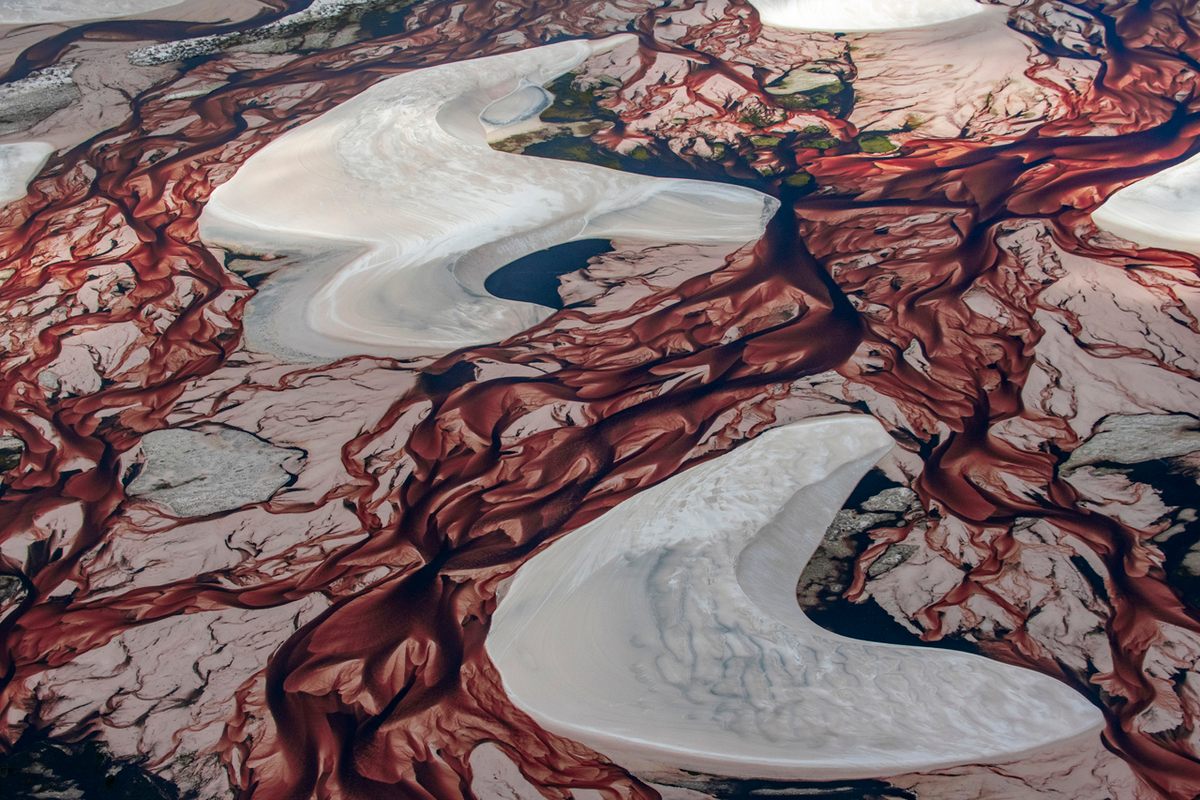 Patches of green (top) also appear amid the red-brown waters and white dunes.