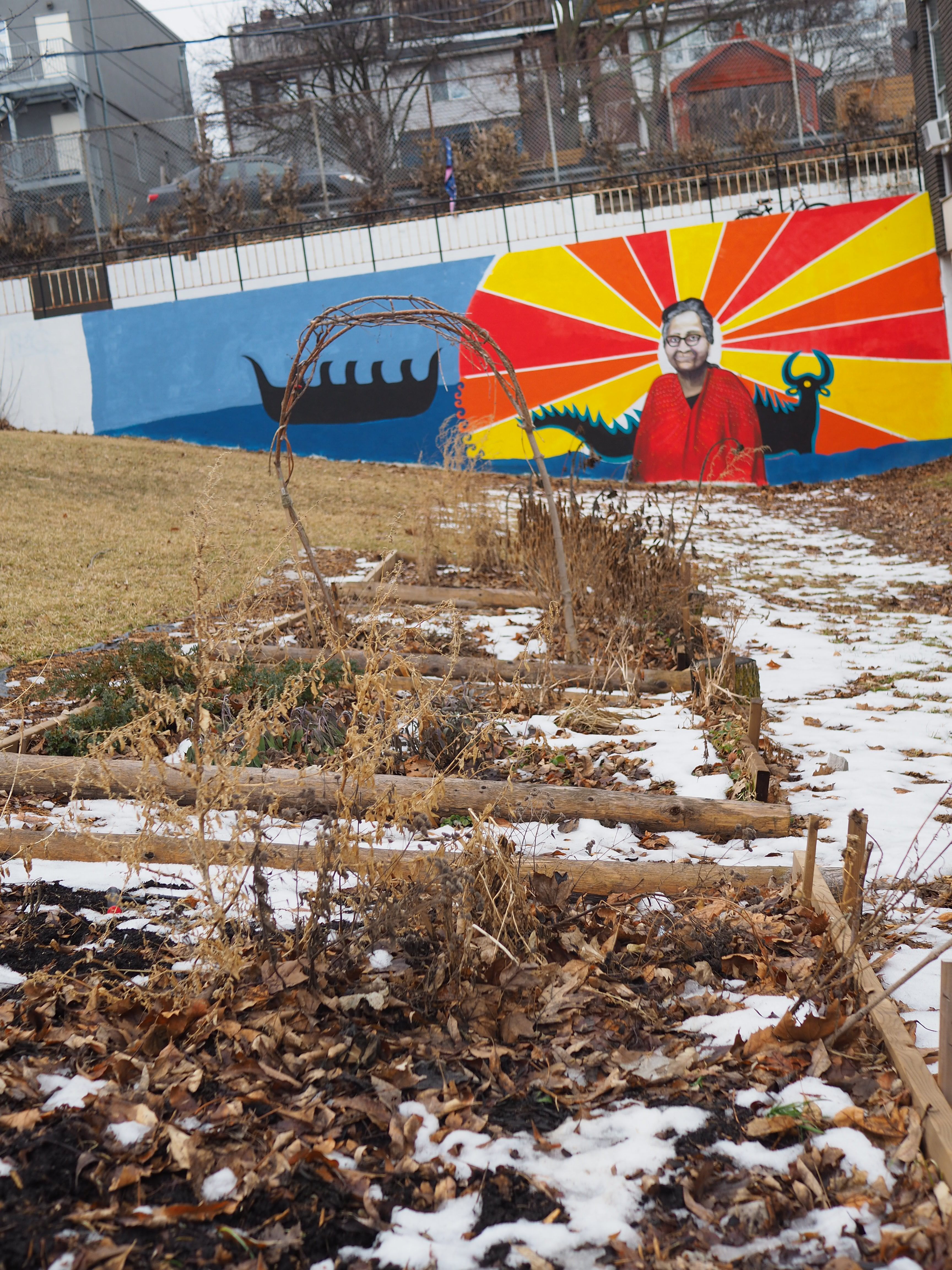 A mural featuring Plains Cree elder Pauline Shirt and a mythical underwater panther decorates the far end of the dormant medicine garden at the Bickford Centre.