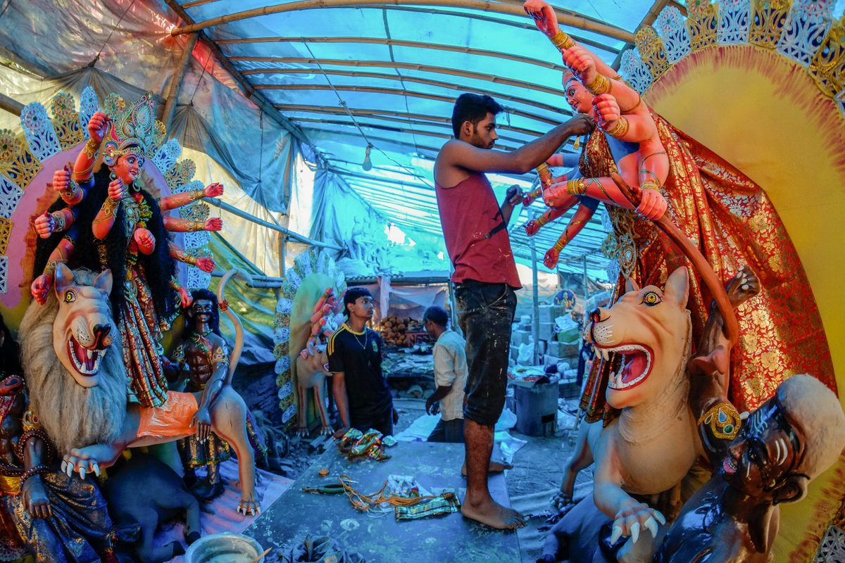 An artist decorates an idol of Durga, a fearsome Hindu Goddess often represented riding a lion.