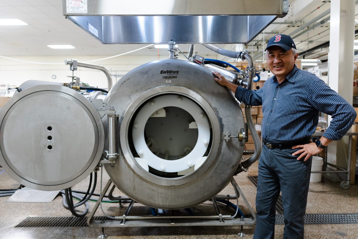 Senior Food Technologist Tom Yang poses next to the vacuum microwave dryer that he uses to preserve foods.