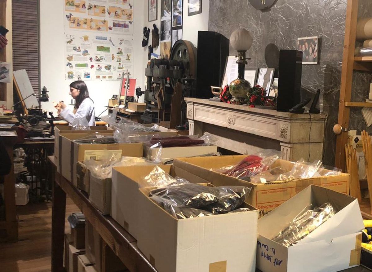 Boxes of gloves fill a portion of Strazzeri's workshop and boutique. At left, an intern works at a sewing machine.