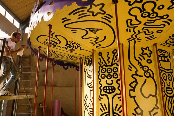 In an undated photo, American artist Keith Haring works on the colorful carousel he designed for the original 1987 Luna Luna. The carousel features three-dimensional characters based on the line-drawn figures he became famous for.