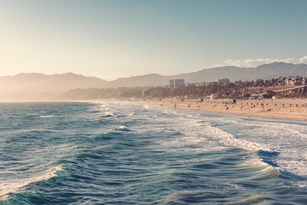 View of Santa Monica Beach and Los Angeles in afternoon sun. Aerial view from above the pacific ocean water.