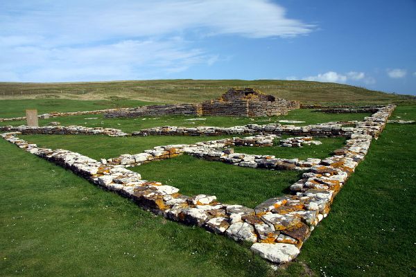 The remains of houses with the church and, on the left, the replica Pictish stone.