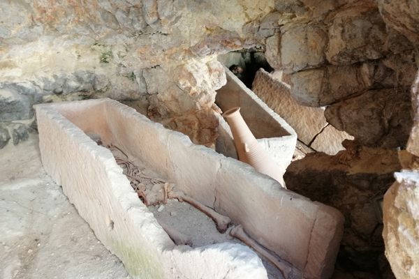 A damaged sarcophagus sits in a stone-walled burial chamber