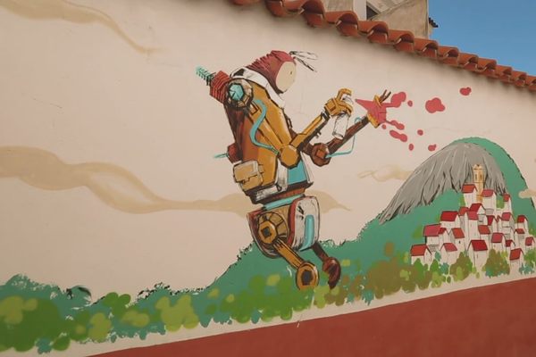 A giant robot spraypaints houses in this mural.