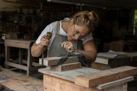 Here, Sigrid Coffin chisels a letter on a beach stone to mark the grave of a family member’s dog. The stone was chosen for its oval shape to resemble the late Dachshund. 