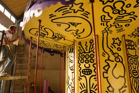 In an undated photo, American artist Keith Haring works on the colorful carousel he designed for the original 1987 Luna Luna. The carousel features three-dimensional characters based on the line-drawn figures he became famous for.