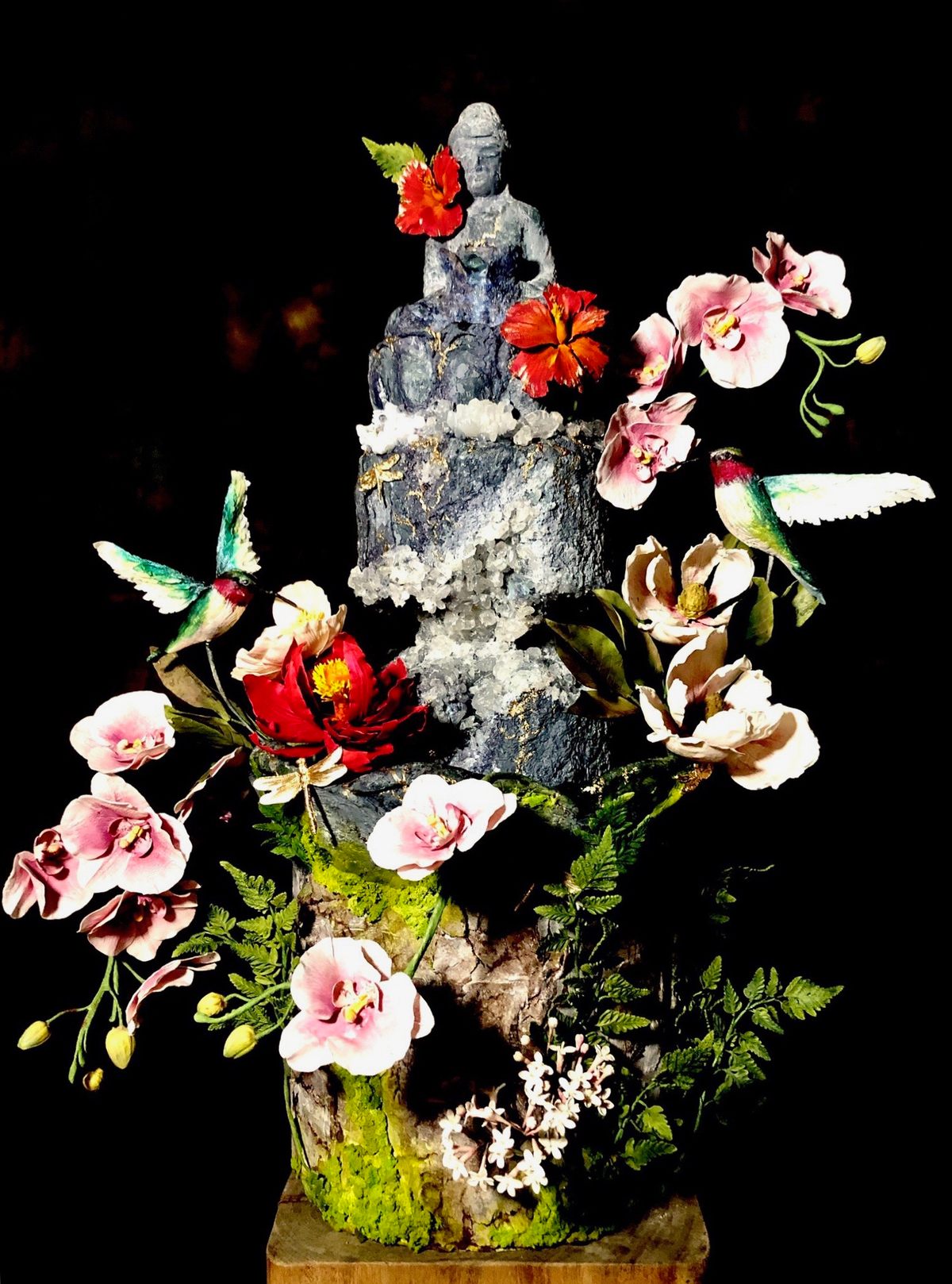 A zen garden cake with an active waterfall emerging from the lap of an edible Buddha sculpture.