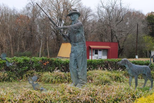 Sculpture of John Rex Gates with a Pointer and Setter behind a covey of quail exploding upward in flight