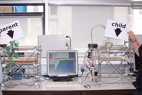 Bowyer and a volunteer, Vik Olliver, pose with the original parent RepRap and its first child. 