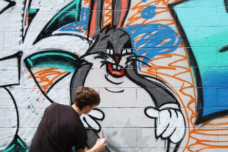 Street artist spray painting internet meme “Chungus” on the wall.