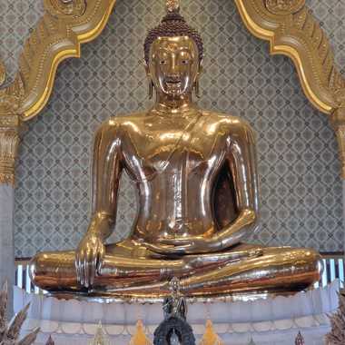 Golden Buddha sits in on a marble pedestal.