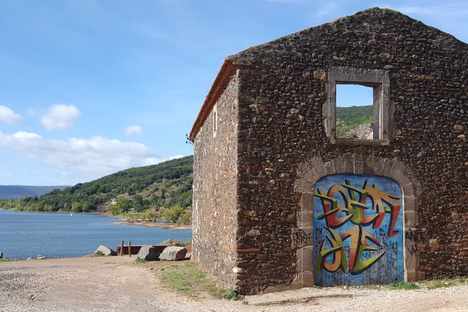 A graffitied former home beside the lake.