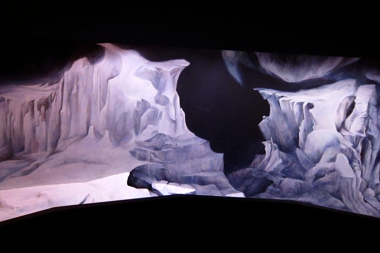 A panoramic painting of jagged, icy white and blue cliffs against a dark background in a dimly lit room.