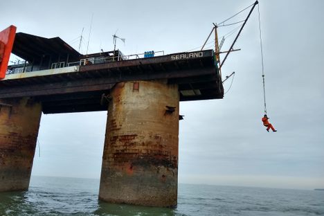 Caretaker Mike Barrington waits as the boat circles around to collect him. It can be difficult to navigate around the platform legs.