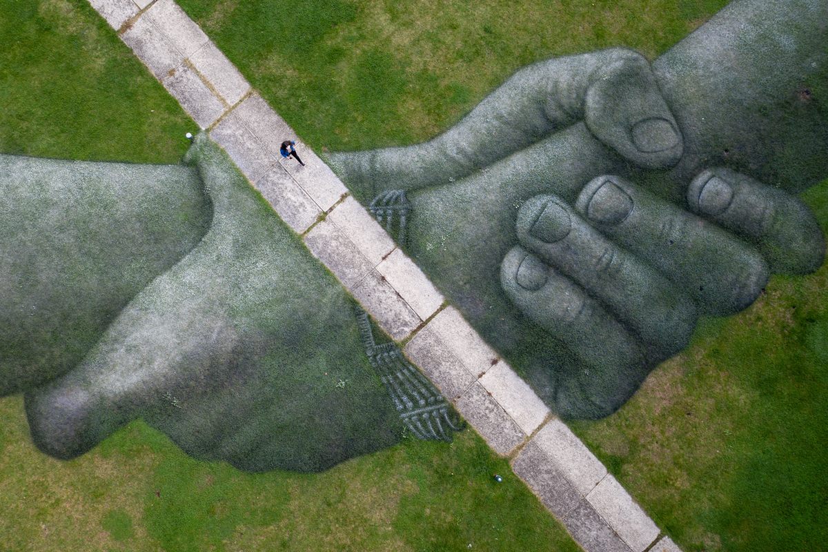 A woman walks through a grass mural by French land artist Guillaume Legros, known as Saype, at Bosporus University in Istanbul, Turkey. The artist's gigantic grass artworks have been completed in many locations around the world, and this series is focused on a symbolic human chain (October 2020). 
