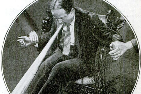 The magician Harry Houdini, who sought to debunk spiritualists and their tools, speaks into a spirit trombone.