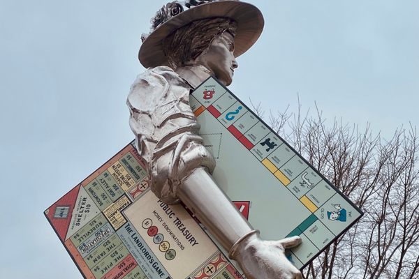 A statue of Lizzie Magie proudly holds up her invention. 
