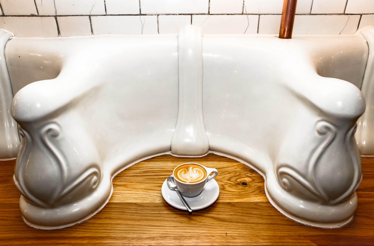 Attendant proudly serves coffee and snacks atop refurbished urinals.  