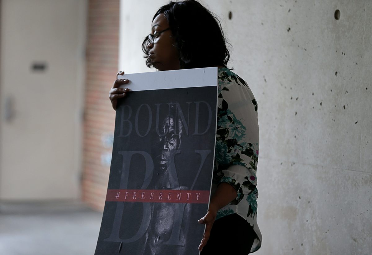 Members of the Lanier family—including Shonrael, pictured here—protested Harvard's collection of images of formerly enslaved people, such as this one of a man named Renty, who was compelled to pose for a photograph commissioned by Louis Agassiz, a 19th-century biologist at the school who used the images to further his ideas about racial inferiority. The Lanier family counts Renty as one of their ancestors and sued Harvard in 2019. The case was dismissed in March 2021.