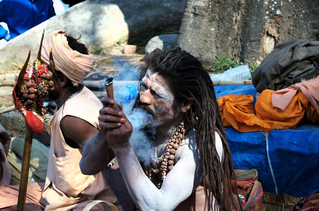 An ascetic devotee of Lord Shiva smokes ganja from a traditional clay <em>chillum</em>.